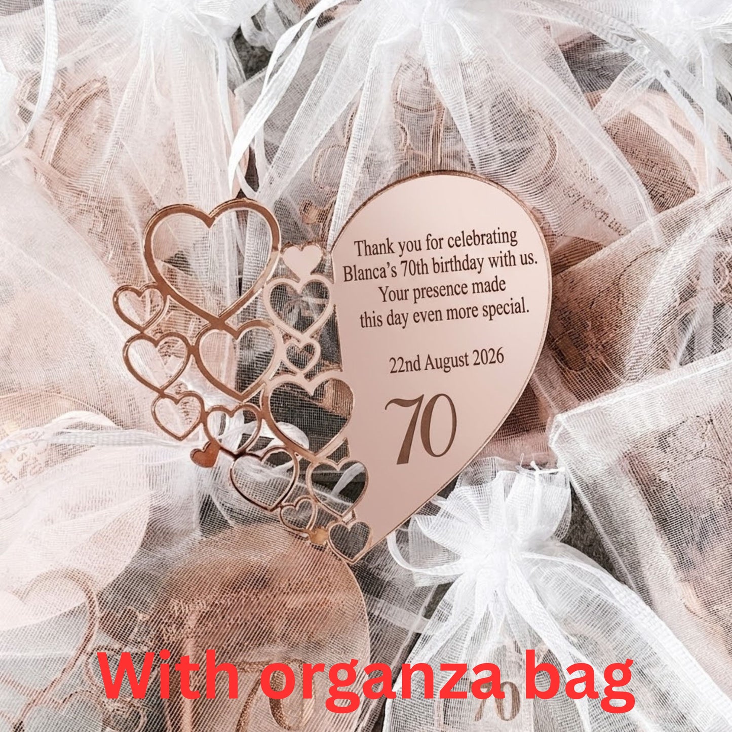 Personalized heart-shaped wooden birthday favor tags with laser-cut heart patterns, shown inside white organza gift bags with red text overlay reading 'With organza bag'.