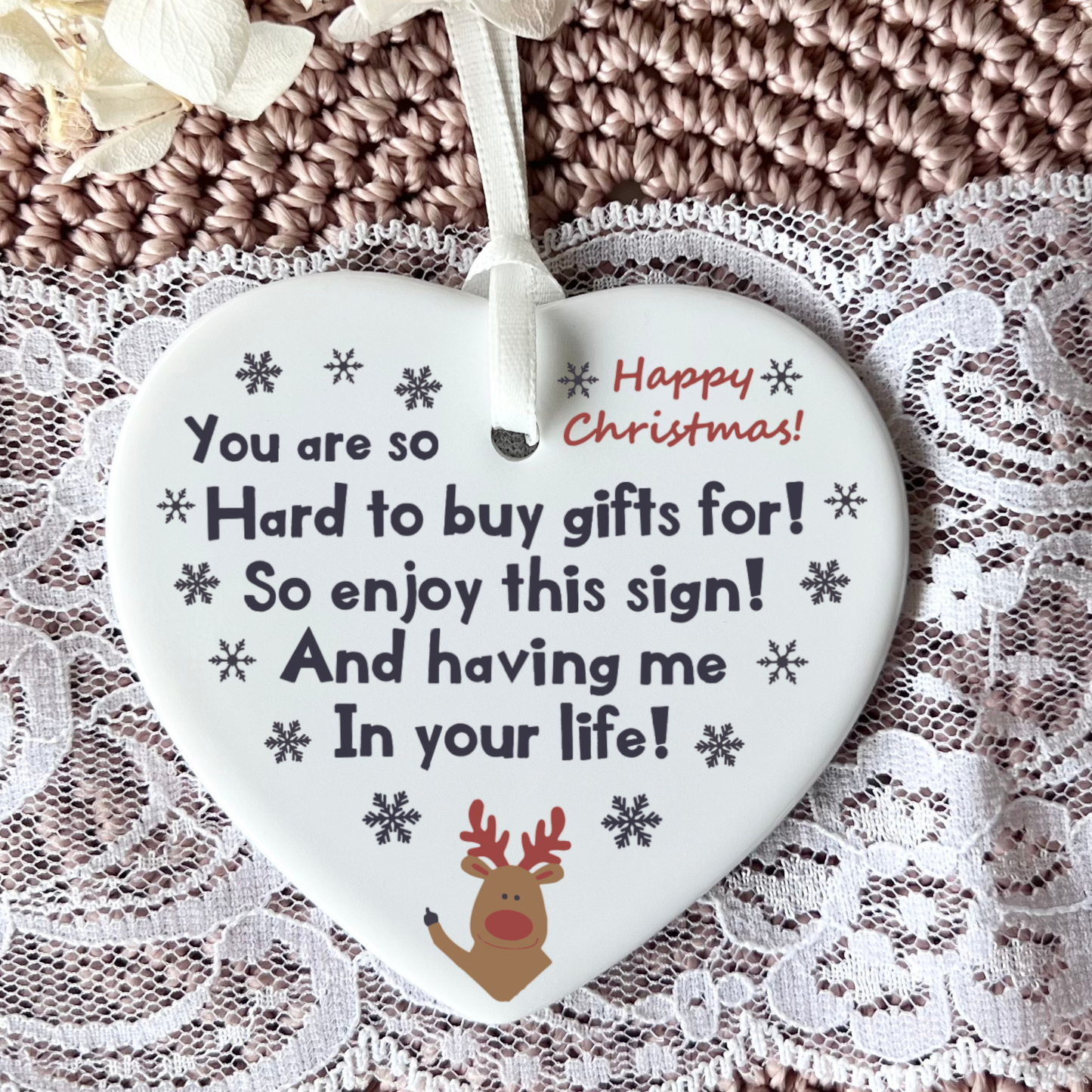 Heart-shaped Christmas ornament with text and reindeer design on a lace background