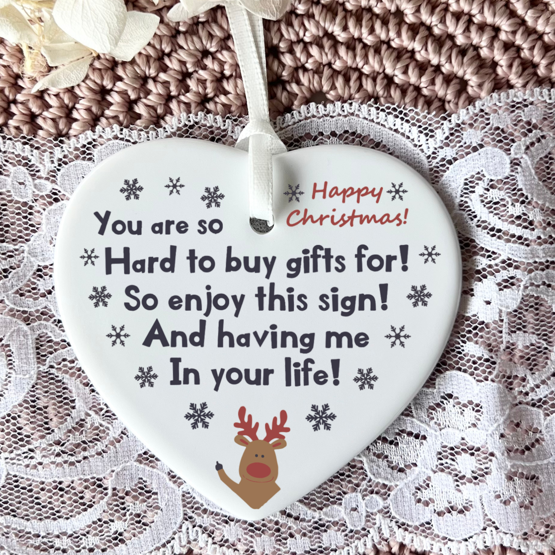 Heart-shaped Christmas ornament with text and reindeer design on a lace background