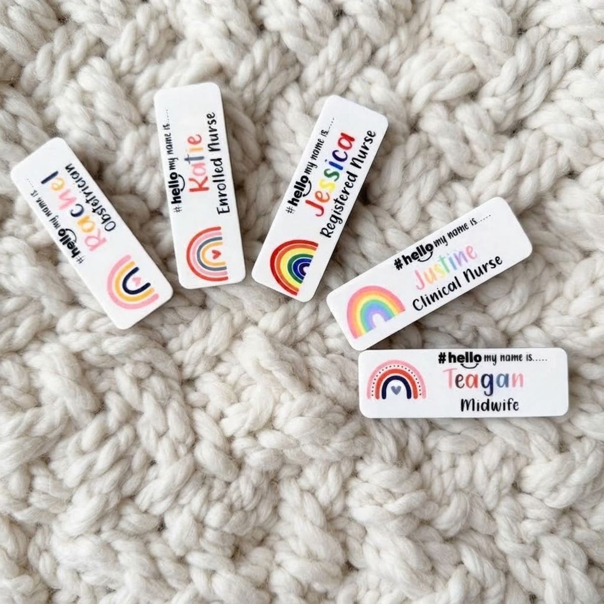 Five white rectangular name tags with colorful rainbow graphics and text such as 'Hello my name is.