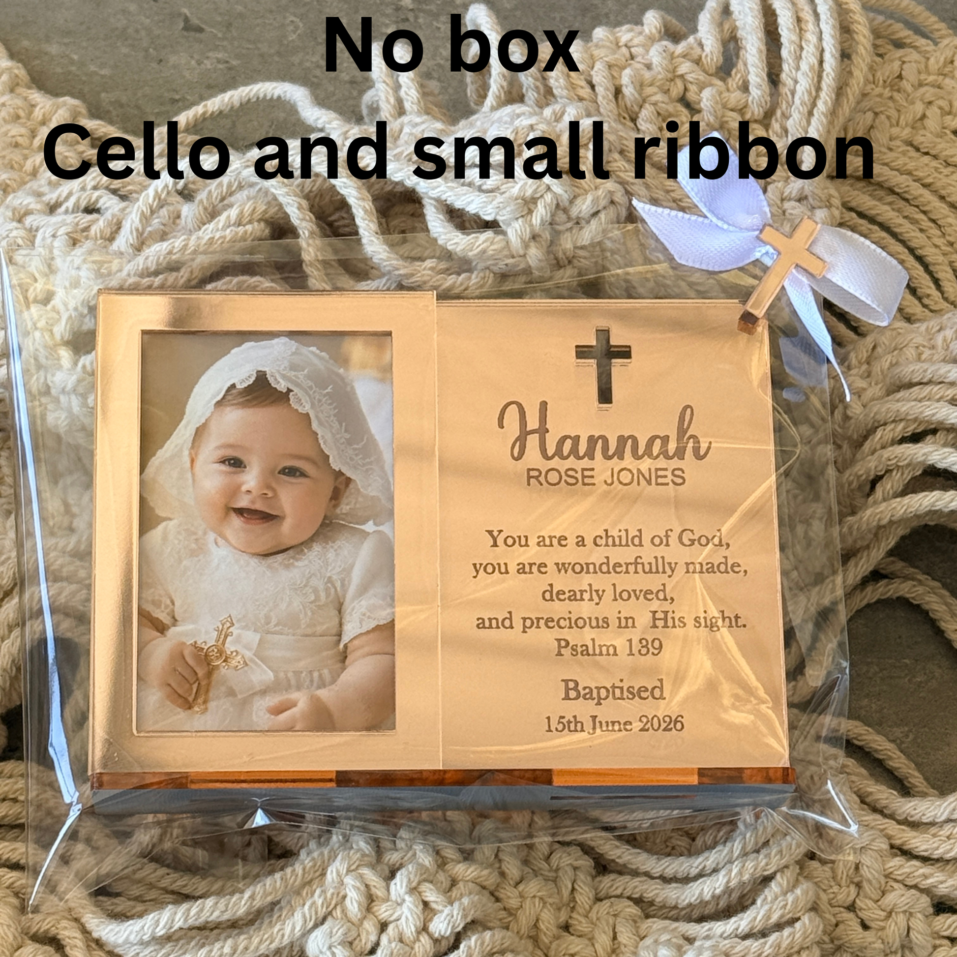 Personalised wooden baptism memorial card in clear cellophane packaging, shown with a baby photo on one side and engraved text on the other. Large text at the top reads 'No box Cello and small ribbon'.