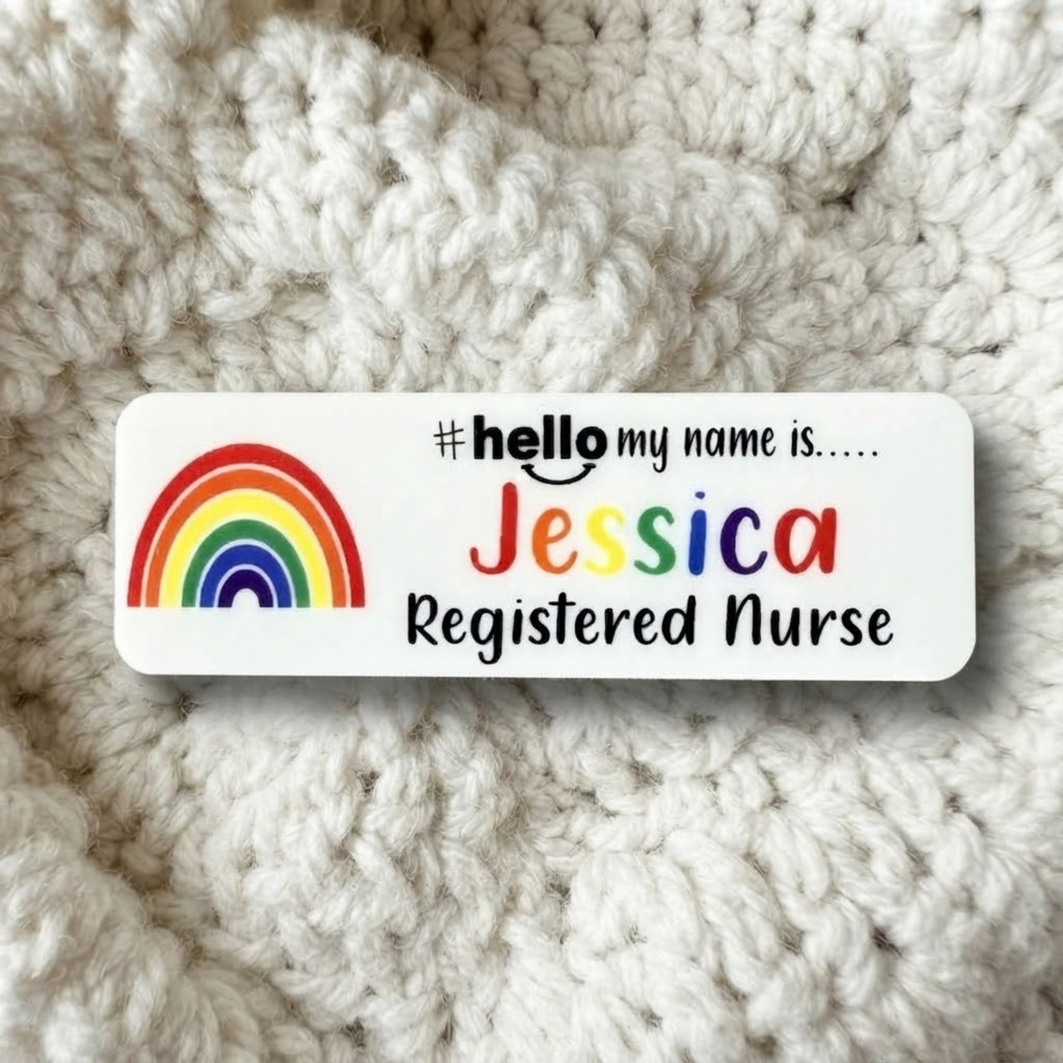 A custom white rectangular name tag with a colorful rainbow graphic and the text '#hello my name is.