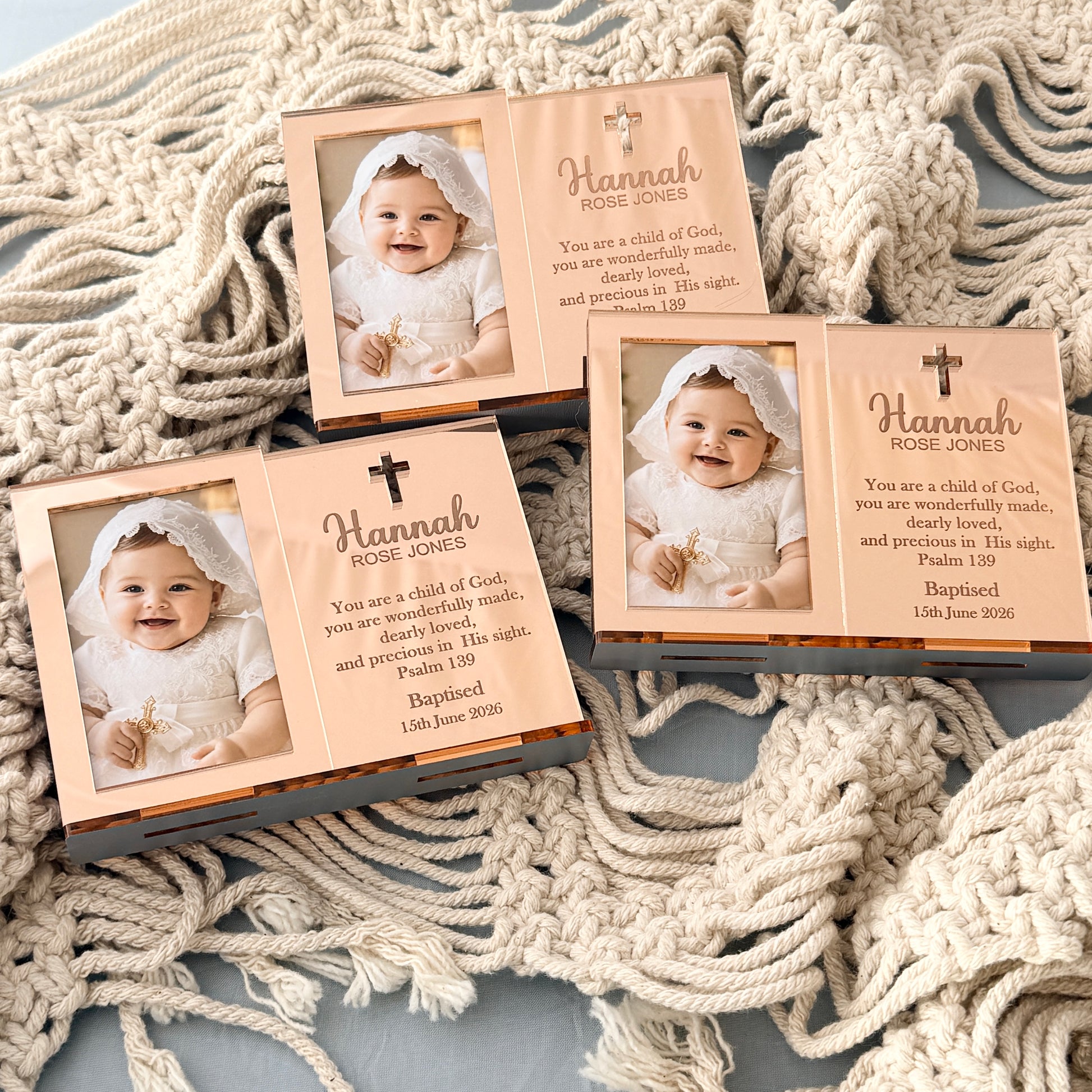 Three personalized baby baptism photo keepsake boxes are arranged on a textured cream knit blanket. The boxes feature a peach-colored interior with a printed photo of a smiling baby in a white outfit, a small gold cross, and a Bible verse.