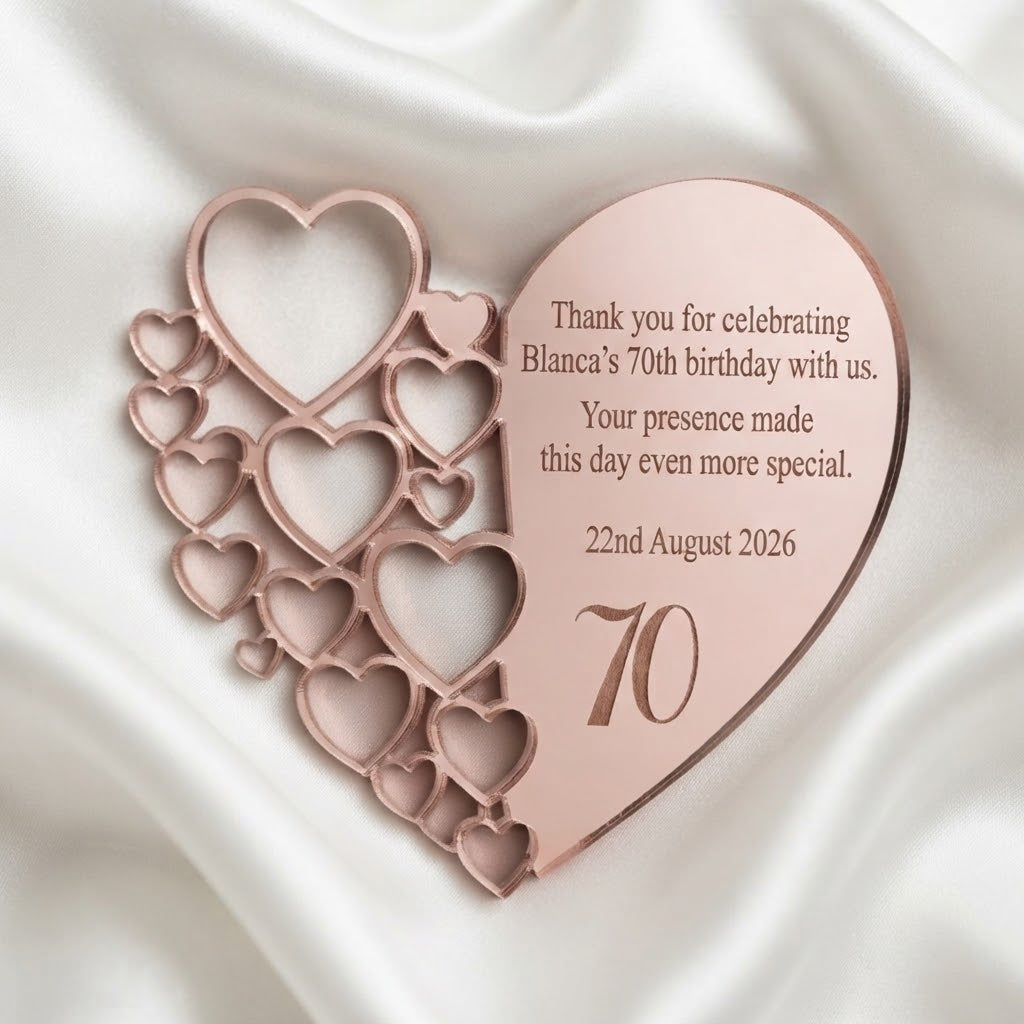 A rose gold heart-shaped wooden fridge magnet with laser-engraved text celebrating a 70th birthday, displayed on a draped white satin fabric background.