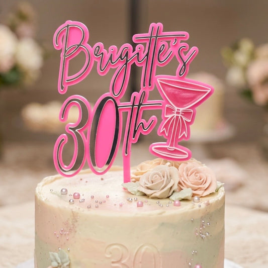 Cake with 'Brigitte's 30th' pink topper on a blurred background