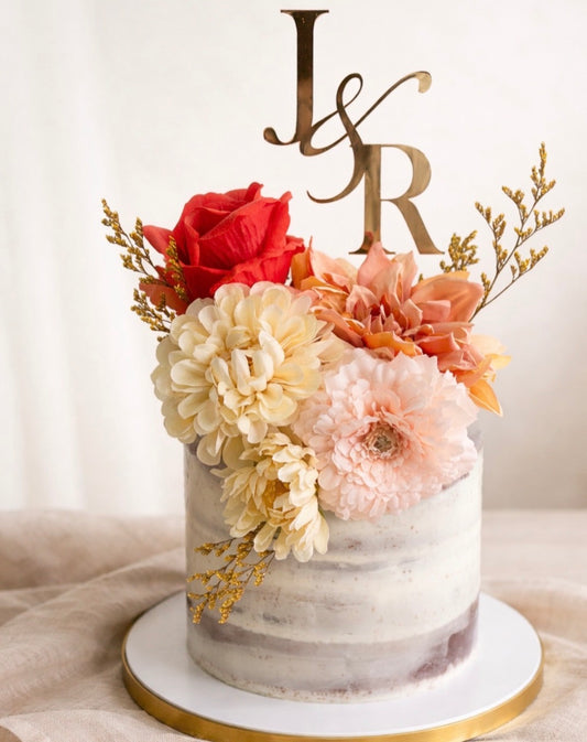Decorative cake with flowers and initials 'J' and 'R' on a white background